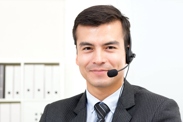 Улыбающийся красивый бизнесмен, носящий микрофонные наушники в качестве оператора
 - Фото, изображение
