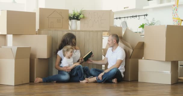 Aile ev taşıma. Ebeveynler ve çocuklar kutuları açma. rahatlatıcı ve karton evinden açmak sonra gülerek aile taşı - Video, Çekim