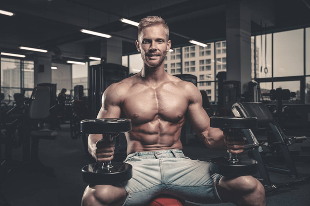 Caucasian sexy fitness male model execute exercise with dumbbell - Fotografie, Obrázek