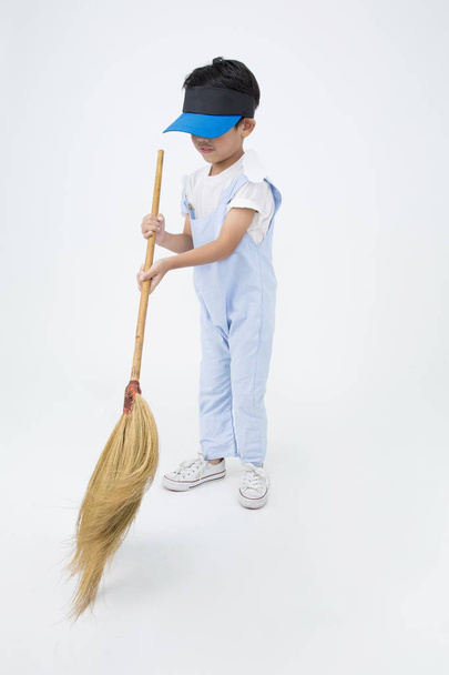Happy asian child with broom cleaning in the house - Фото, зображення