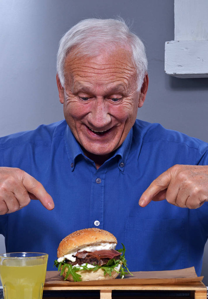 senior man with tasty burger  - Foto, Bild