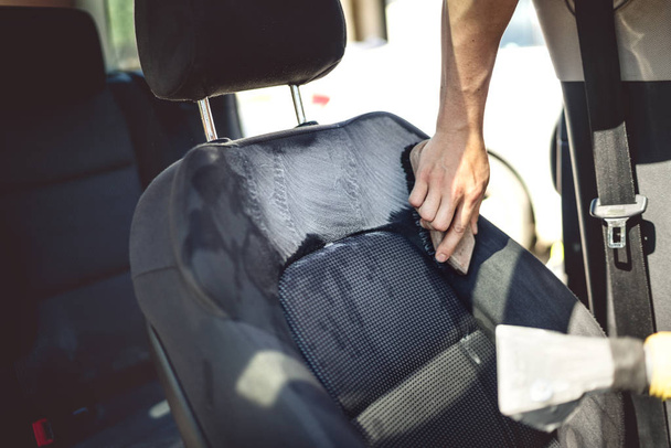 Concetto di cura dell'auto - dettaglio del sedile del conducente utilizzando strumenti e detergenti professionali
 - Foto, immagini