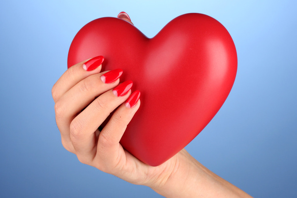 Κόκκινη καρδιά στο χέρι της γυναίκας σε φόντο χρώμα - Φωτογραφία, εικόνα