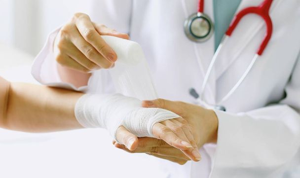 Close-up of female doctor with stethoscope bandaging hand of patient. - Valokuva, kuva