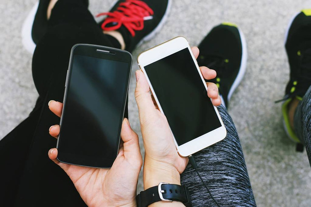 Kaksi nuorta tyttöä käyttää älypuhelinta ulkona, Ystävät chattering mobiilisovelluksella
. - Valokuva, kuva