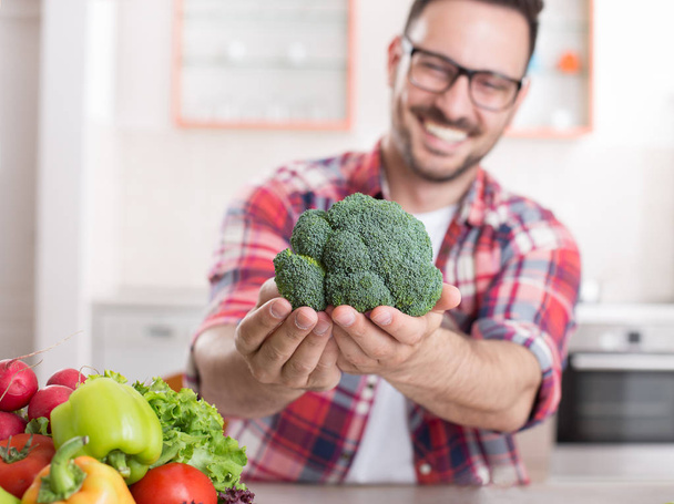 Hombre mostrando verduras en la cocina
 - Foto, Imagen