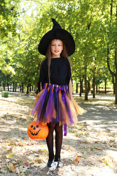 Beautiful girl witch and basket of candies in the park, outdoors - Фото, изображение