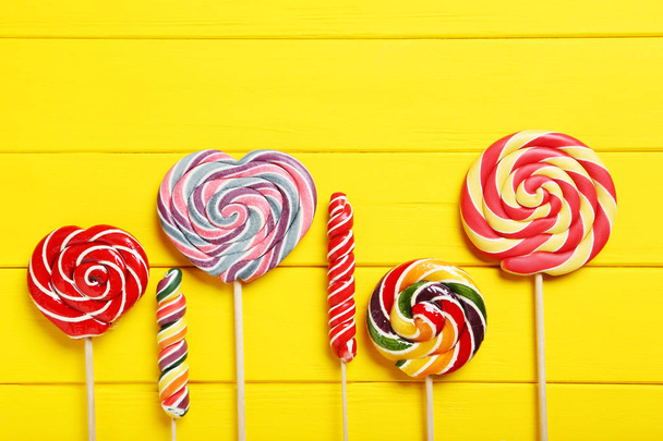 Sweet lollipops on yellow table - Фото, изображение