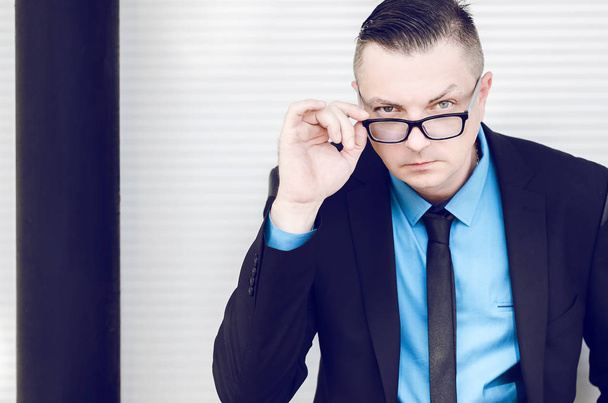 businessman in a suit holding eyeglasses - Φωτογραφία, εικόνα
