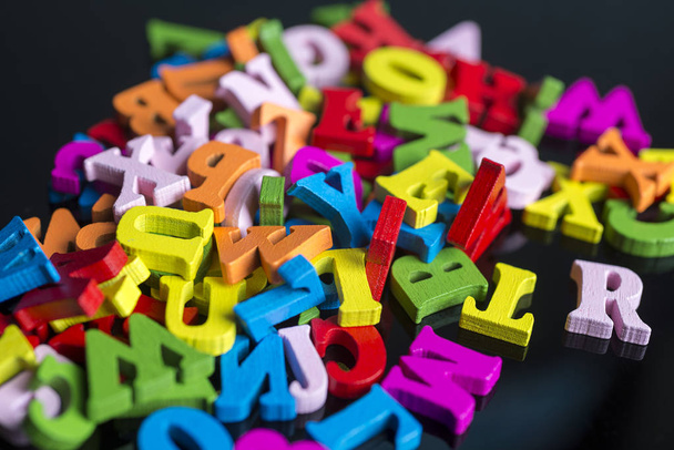 A lot of colored letters on a black background. - Фото, изображение