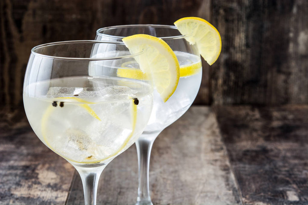 Glass of gin tonic with lemon on wooden background - 写真・画像
