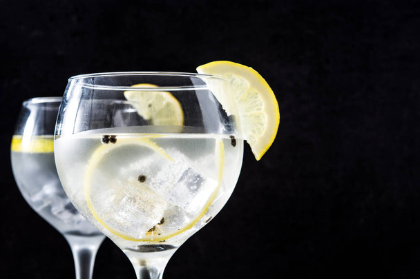 Glas Gin Tonic mit Zitrone auf schwarzem Stein Hintergrund - Foto, Bild