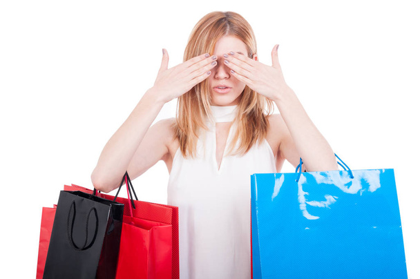 Mujer sosteniendo bolsas de compras y cubriendo sus ojos
 - Foto, Imagen