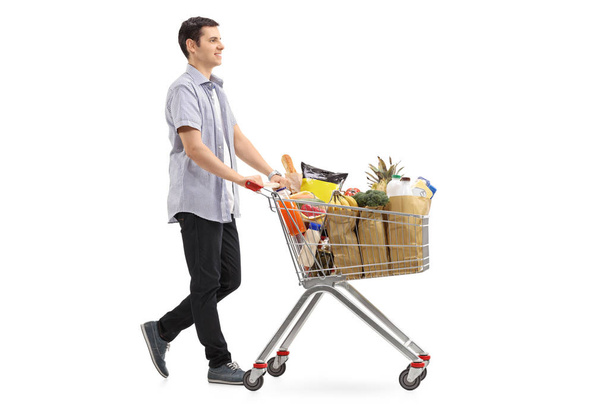 man pushing a shopping cart filled with groceries - Foto, afbeelding