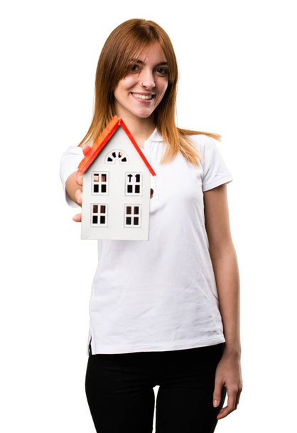 Ευτυχής όμορφη νεαρή κοπέλα που κρατά ένα μικρό σπίτι - Φωτογραφία, εικόνα