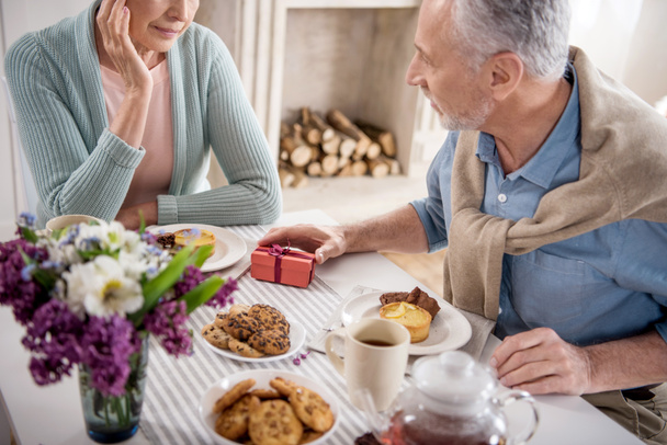 mies esittää lahja vaimolle aamiaisen aikana
 - Valokuva, kuva