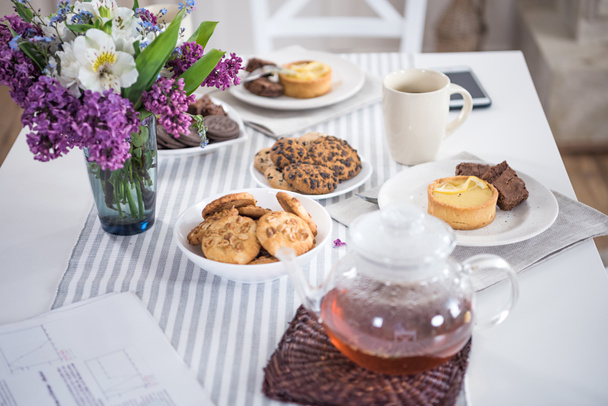 lilac flowers with tea and various pastry - Φωτογραφία, εικόνα