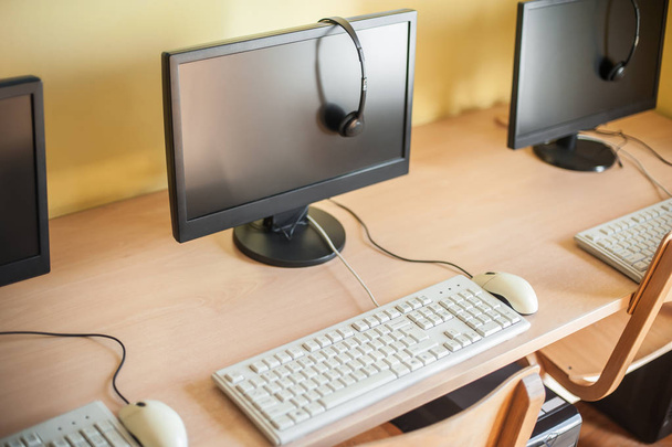 Rzędu komputerów ze słuchawkami na biurku w szkole podstawowej - Zdjęcie, obraz