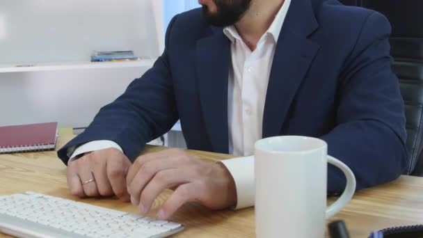 A pleased businessman sittingin his office working at his computer - Felvétel, videó