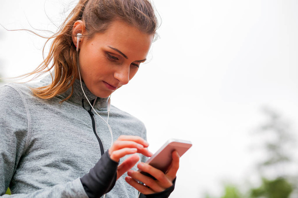 Athletic woman before start running setting up her smart phone app - 写真・画像