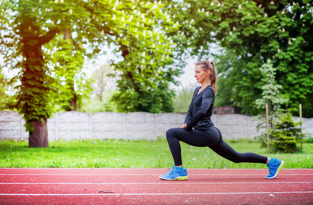 Athletic woman stretching on running track before training, healthy lifestyle - Φωτογραφία, εικόνα