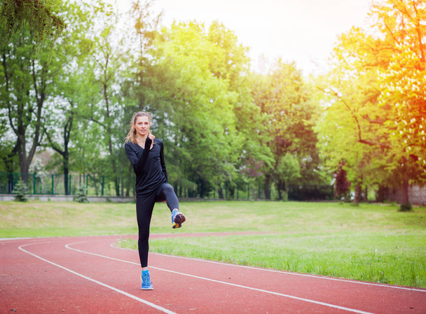 Mujer atlética estirándose en pista de atletismo antes del entrenamiento, estilo de vida saludable
 - Foto, imagen