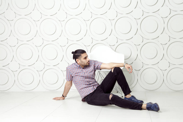 Young bearded fashion model in casual style is posing near white circle wall background.  - Fotografie, Obrázek