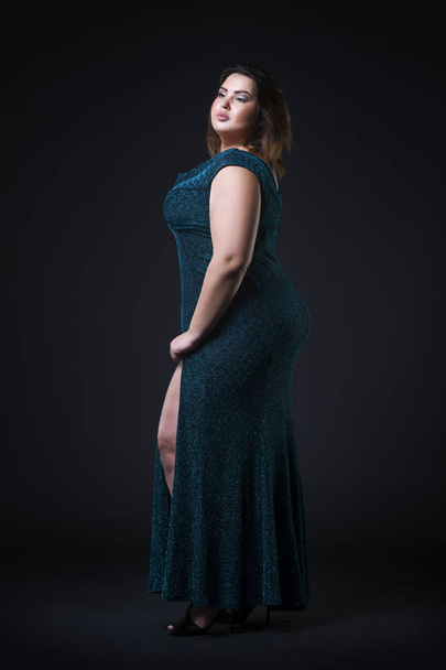 Plus size fashion model in green evening dress, fat woman on black background, overweight female body - Фото, изображение