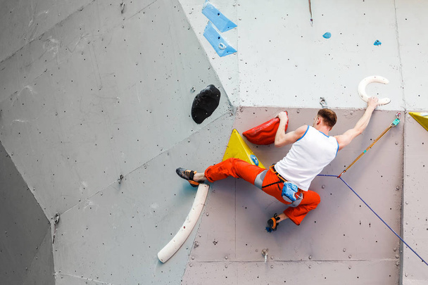Esportista de alpinista masculino pendurado na parede de escalada artificial, competição em competição de dificuldade
 - Foto, Imagem