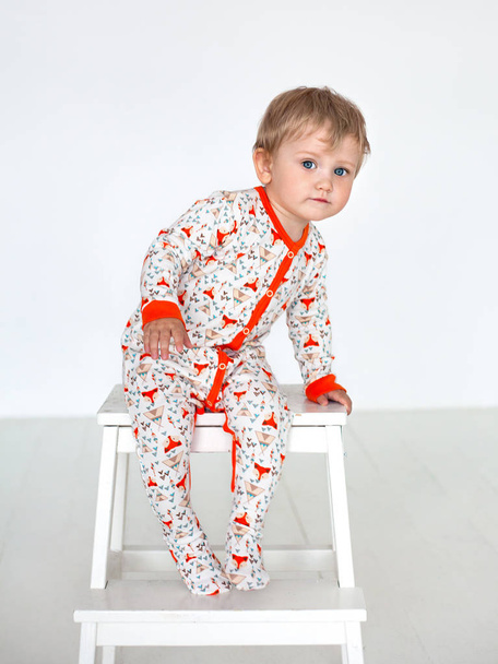 The kid in the orange slip sits on a chair - Fotografie, Obrázek