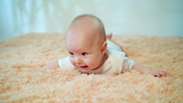 Baby liegt auf dem Bauch auf einem kuscheligen Teppich - Filmmaterial, Video