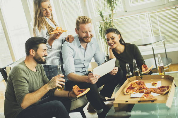 Amigos comendo pizza no interior moderno
 - Foto, Imagem