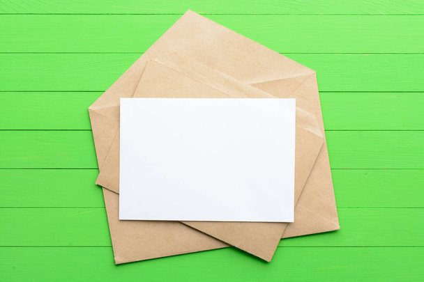 Un pedazo de papel en blanco con un sobre sobre sobre fondo de madera verde
 - Foto, Imagen