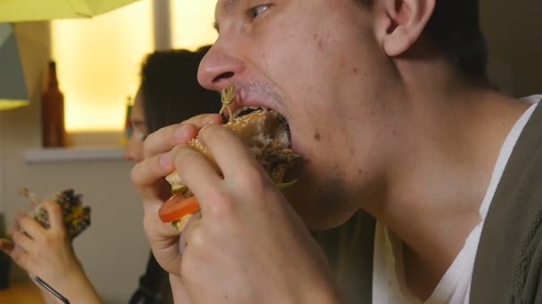 Blíže se člověk kousne a jí hamburger v kavárně - Záběry, video