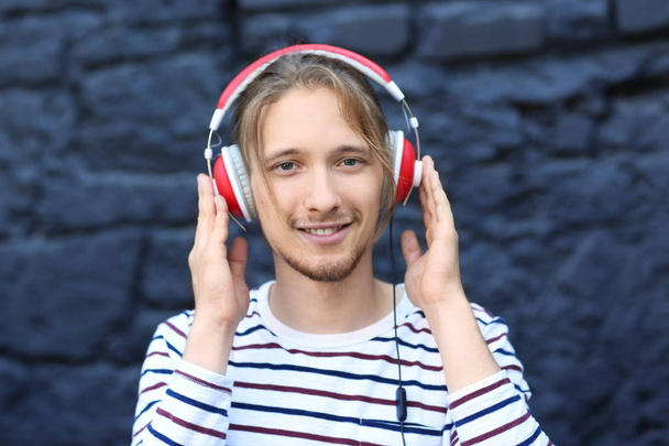 Handsome young man listening to music outdoors - Fotografie, Obrázek