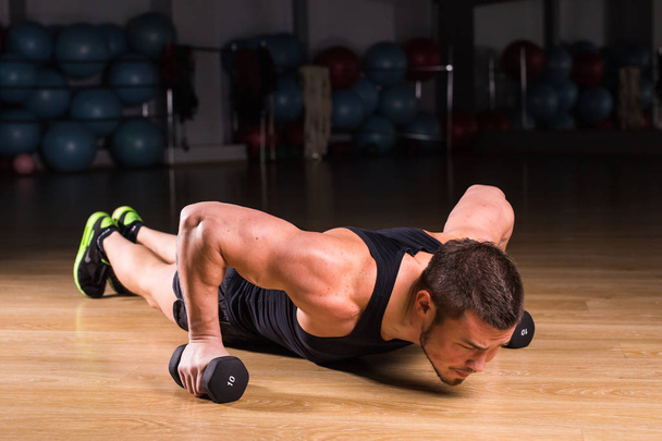 Young Man Athlete Doing Pushups With Dumbbells As Part Of Bodybuilding Training. - Foto, Imagen
