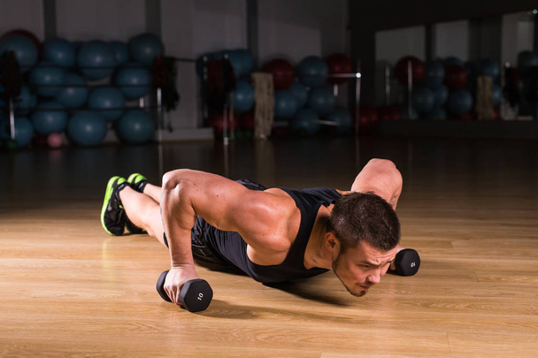 Young Man Athlete Doing Pushups With Dumbbells As Part Of Bodybuilding Training. - Photo, Image
