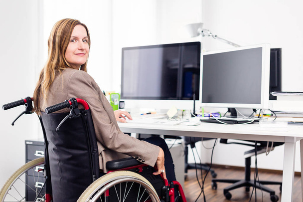 Woman Sitting In Wheelchair Working In Modern Office - Foto, imagen