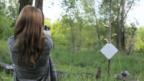 Κορίτσι μελαχρινή γυρίσματα σε στόχους από ένα πιστόλι στη φύση - Πλάνα, βίντεο