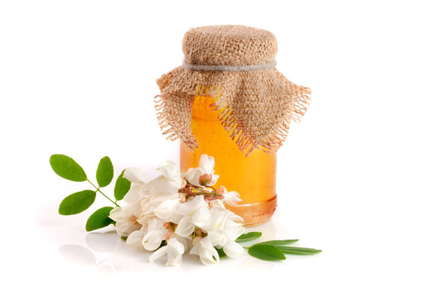 Jar of honey with flowers of acacia isolated on white background - Фото, изображение