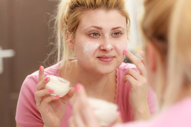 Woman applying face cream with her finger - Foto, afbeelding
