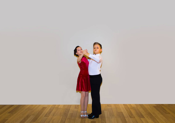 Мальчик и девочка позируют в танцевальной студии на сером. Концепция бальных танцев
 - Фото, изображение