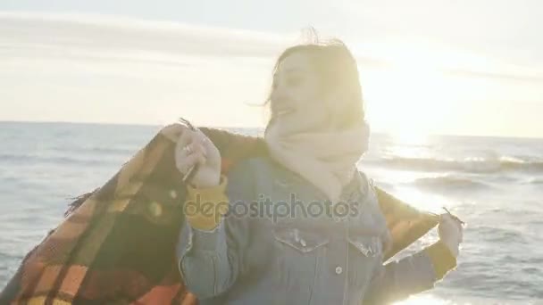 Giovane bella donna alza le mani con plaid sulla riva del mare. Felice femmina godendo il tramonto sulla spiaggia
. - Filmati, video