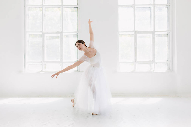 Young and incredibly beautiful ballerina is posing and dancing in a white studio - Фото, зображення