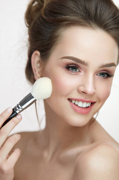Beauty Face Makeup. Beautiful Smiling Girl Applying Loose Blush - Fotó, kép