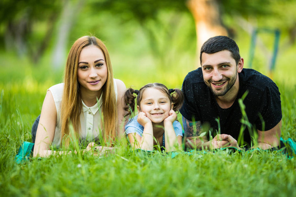 portret rodziny szczęśliwy trzy leżące na trawniku, zabawy - Zdjęcie, obraz