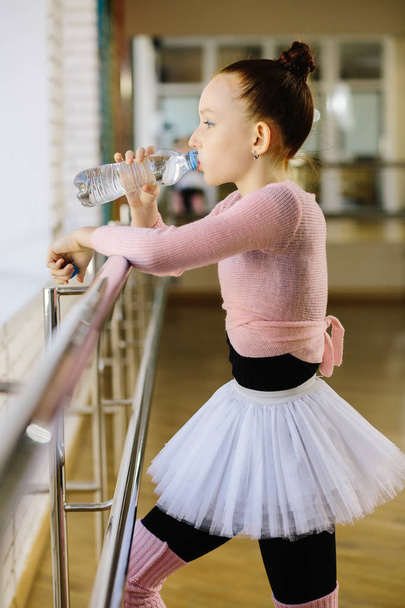 Girl ballet dancer drinking water in ballet class - 写真・画像