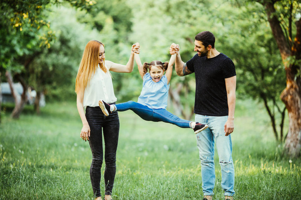 happy mother, father and little girl running together and have fun in summer park - Foto, Imagen