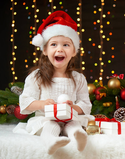 child girl portrait in christmas decoration, happy emotions, winter holiday concept, dark background with illumination and boke lights - Photo, Image