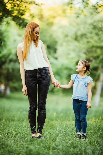 Mother and daughter having fun in the park. Happy family concept. Beauty nature scene with family outdoor lifestyle. Happy family resting together. Happiness and harmony in family life. - Photo, Image
